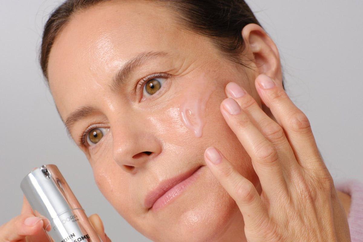 Woman in her 50s applying serum to her cheek