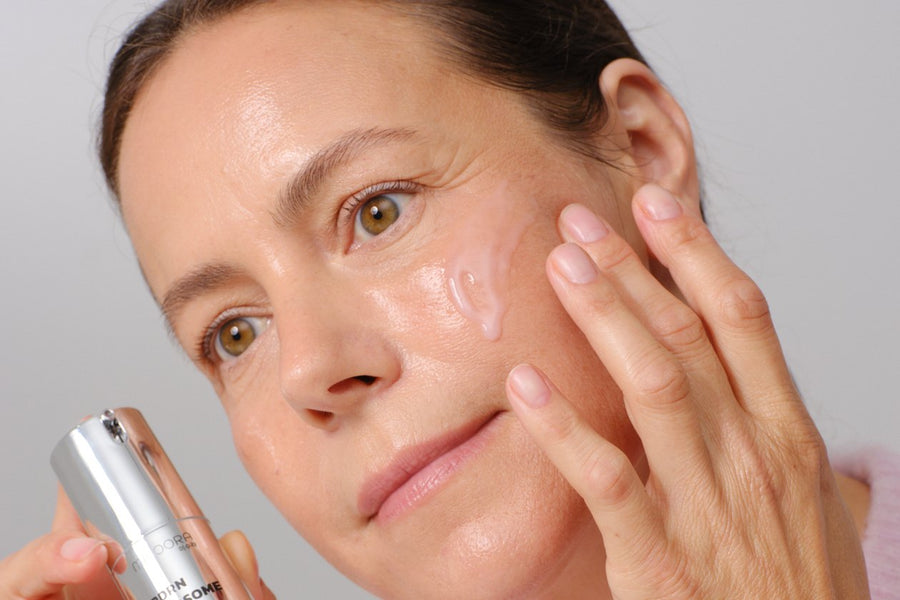Woman in her 50s applying serum to her cheek