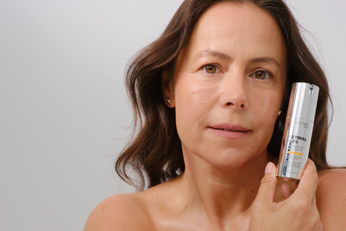 Woman holding MISOORA Retinal 0.2% Barrier Serum next to her cheek