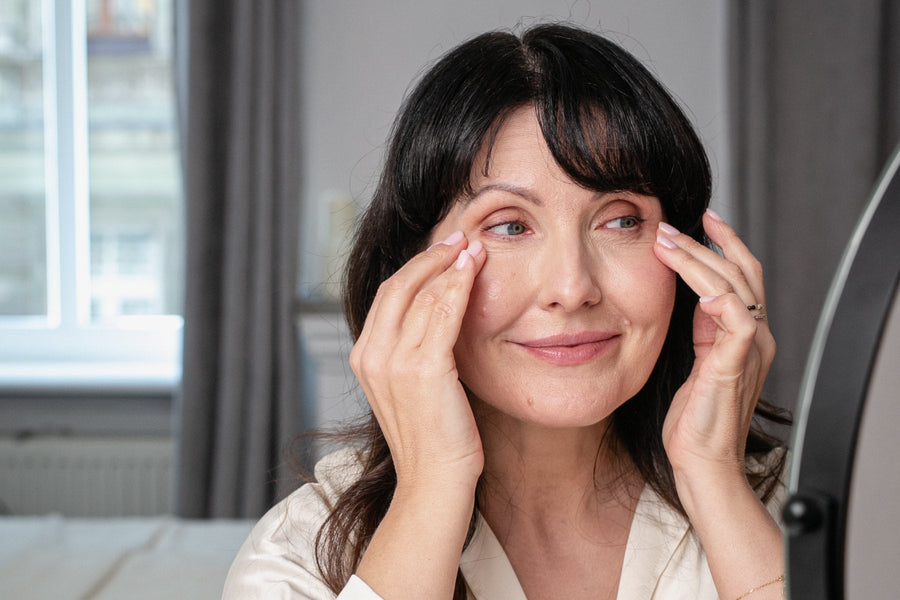Woman in her 50s gently pressing her fingertips along the skin around her eyes